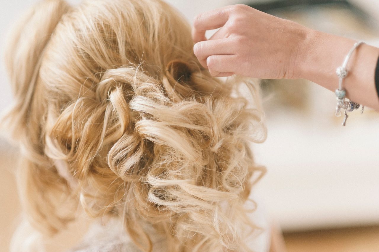 services-01 A professional hairstylist creates a blonde bridal updo for a wedding.