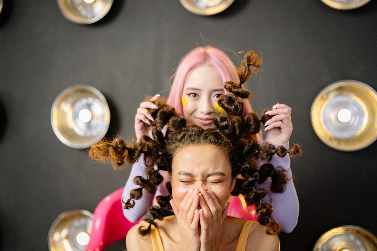 hero-img-02 Two young women with creative hairstyles having fun in a stylish studio setting.