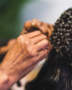 Hand gently touching and feeling textured ponytail braids on Black hair during maintenance routine, demonstrating proper handling technique